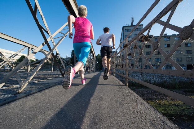 Gesundes reifes Paar Joggen in der Stadt am frühen Morgen mit Sonnenaufgang im Hintergrund