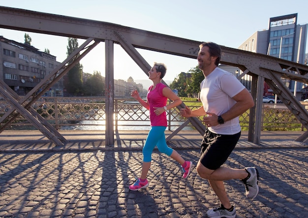 Gesundes reifes Paar Joggen in der Stadt am frühen Morgen mit Sonnenaufgang im Hintergrund