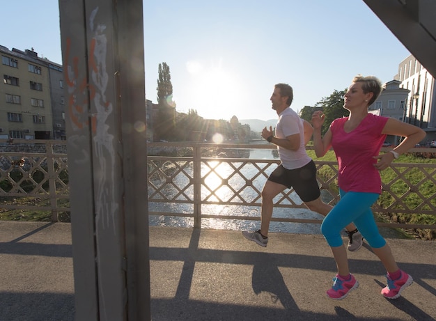 Gesundes reifes Paar Joggen in der Stadt am frühen Morgen mit Sonnenaufgang im Hintergrund