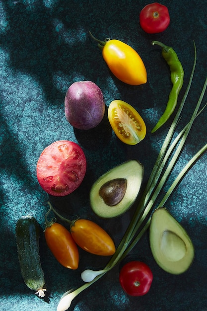 Gesundes saisonales Gemüse rote und gelbe Tomaten Zwiebel lila Kartoffeln Avocado im Schatten