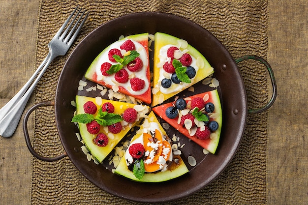 Gesundes sauberes Essen Ernährung und Ernährung saisonales Sommerkonzept Wassermelonenpizza mit Beerenfrüchten Joghurt-Feta-Käse auf einem rustikalen Holztisch Draufsicht flach lag Hintergrund