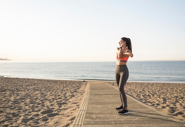 Gesundes Sportmädchen, das am frühen Morgen Dehnübungen am Strand macht