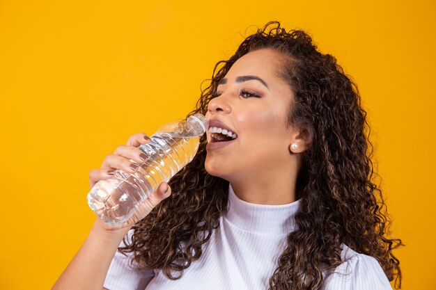 Gesundes Trinkwasser der jungen Frau auf gelbem Hintergrund mit Platz für Text.