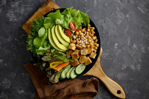 Gesundes und leckeres pflanzliches Lebensmittelkonzept gegrilltes Tofu mit Kichererbsen, Nüssen, Tomaten, Avocado-Slides und grünem Salat, Gemüse, Top-View