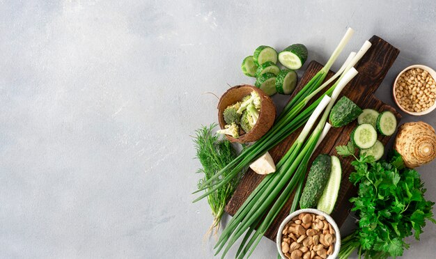 Gesundes veganes Essen vegetarisches Kochkonzept. Holzschneideküchenbrett mit frischem grünem Gemüse, Kräutern und Getreide auf heller Hintergrundoberansicht