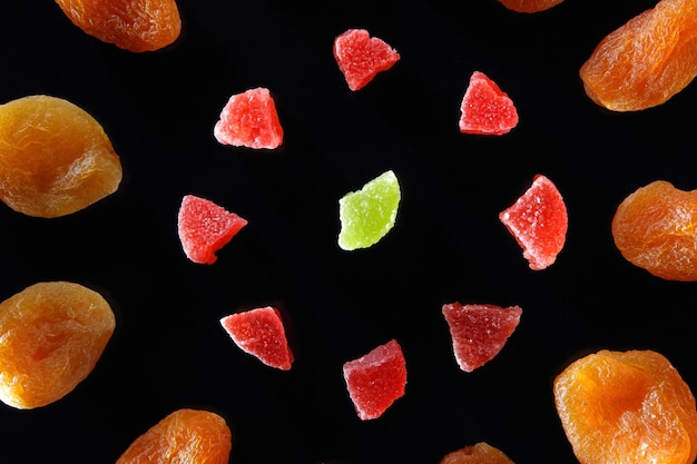 Gesundes vegetarisches Essen auf einem Tisch in der Nähe Bunte kandierte Früchte und getrocknete Aprikosen auf einem schwarzen Teller