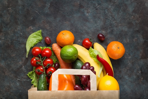 Gesundes vegetarisches Essen in einer Papiertüte Gemüse und Obst auf einer Dunkelheit