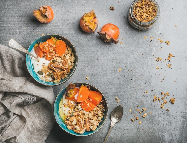 Gesundes vegetarisches Frühstück in bunten Schüsseln über grauem Betonhintergrund