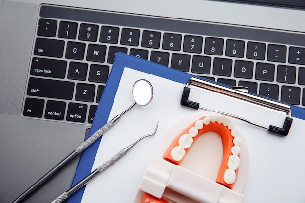 Gesundes Zahnmodell mit Zahnwerkzeug auf weißem Tisch in der Zahnarztpraxis. Zahnhygienekonzept