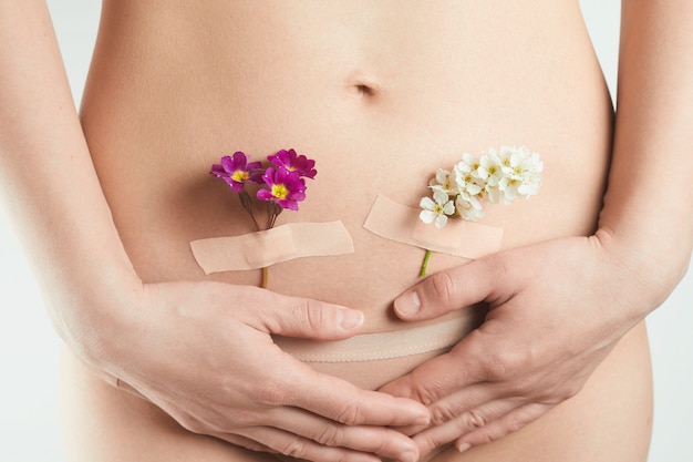 Foto gesundheit des weiblichen fortpflanzungssystems. eine schöne frau mit blumen auf ihrer haut. konzept für schwangerschaft und gynäkologie