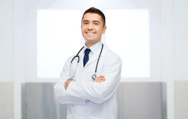 Gesundheits-, Berufs-, Menschen- und Medizinkonzept - lächelnder männlicher Arzt im weißen Kittel mit Stethoskop