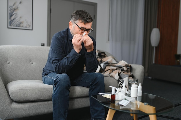 Gesundheits-Grippe-Hygiene und Personenkonzept Kranker Senior mit Papiertuch, der sich zu Hause die Nase weht