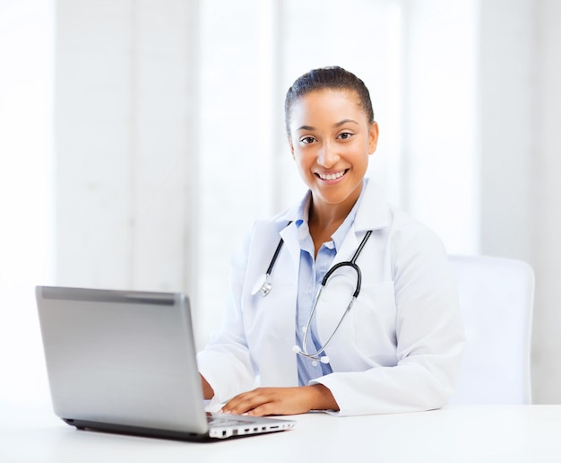 Gesundheits-, Medizin- und Technologiekonzept - afrikanische Ärztin mit Laptop-PC