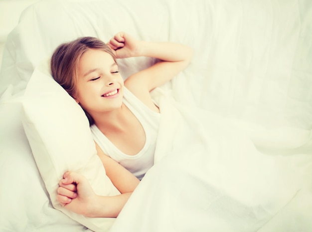 Gesundheits-, schönheits- und kindheitskonzept - lächelndes mädchen, das zu hause im bett aufwacht