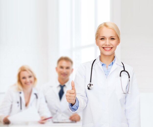 Gesundheits- und Medizinkonzept - lächelnde Ärztin mit Stethoskop, die Daumen nach oben zeigt