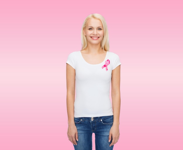 gesundheits- und medizinkonzept - lächelnde frau im leeren t-shirt mit rosa brustkrebsbewusstseinsband