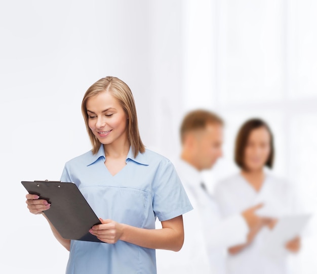 Gesundheits- und Medizinkonzept - lächelnde Ärztin oder Krankenschwester mit Zwischenablage