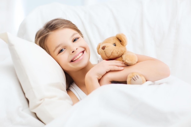 Gesundheits- und Schönheitskonzept - kleines Mädchen mit Teddybär, das zu Hause schläft