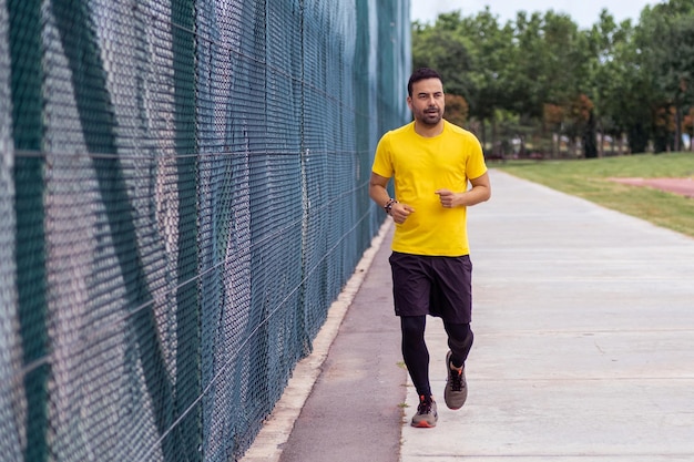 Gesundheitsbewusster Mann läuft auf einem Sportplatz in einem städtischen Park Fitness und Körperentwicklung