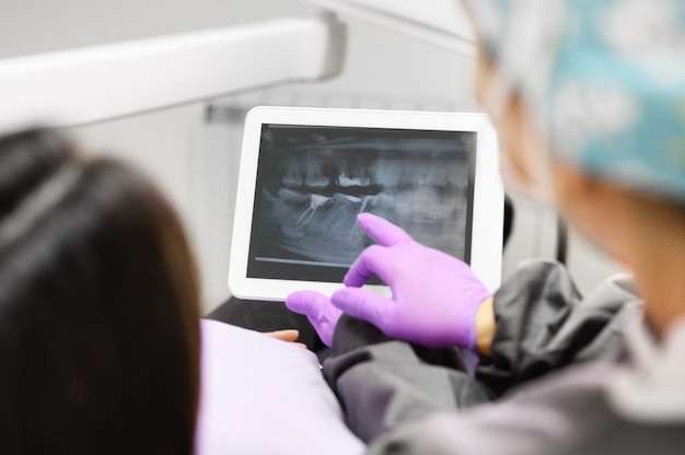 Gesundheitskonzept - Zahnärztin zeigt Tablet-Computer einer Patientin in der Zahnklinik.