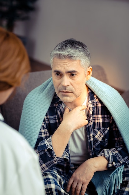 Gesundheitsproblem. angenehm gut aussehender mann, der mit seinem arzt spricht, während er sich über halsschmerzen beschwert