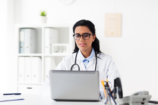 Gesundheitswesen, Technologie, Menschen und Medizin Konzept - weibliche Ärztin in weißem Mantel mit Laptop-Computer im Krankenhaus