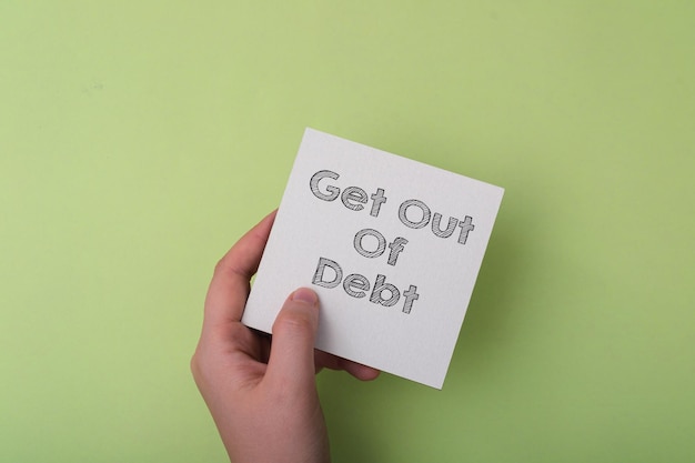 Get Out Of Debt Tex auf einem weißen Blatt Papier in den Händen eines Mannes