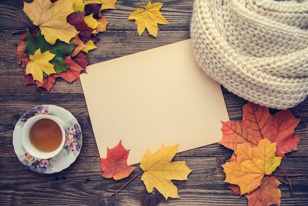 Getöntes Bild mit Herbstlaub, einer Tasse Tee und einem Notizbuch