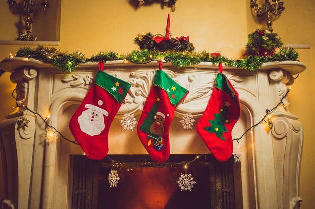 Getöntes Foto von drei roten Weihnachtssocken, die am Kamin im Haus hängen