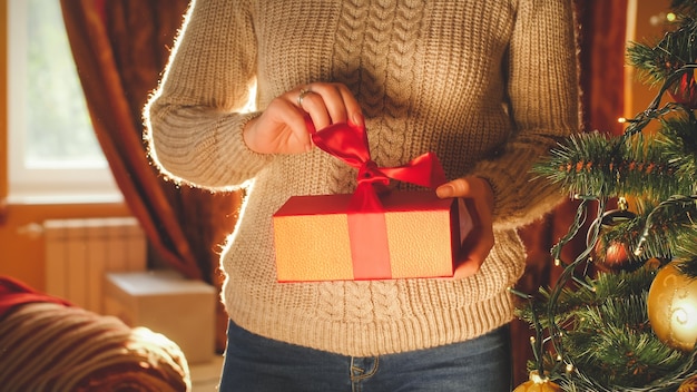 Getontes Bild der jungen Frau, die Weihnachtsgeschenkbox auspackt und öffnet