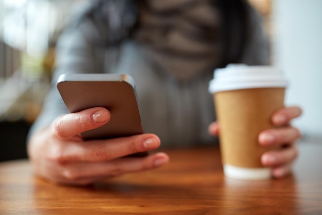 Getränke, Menschen, Technologie und Lifestyle-Konzept - Nahaufnahme einer Frau mit Smartphone und Kaffee am Café-Tisch