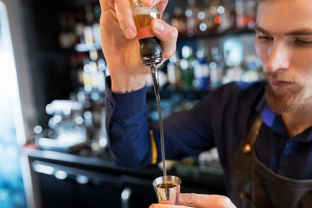 Getränke-, Menschen- und Luxuskonzept - Barmann mit Shaker, der Alkohol aus der Flasche in einen Krug gießt und an der Bar einen Cocktail zubereitet