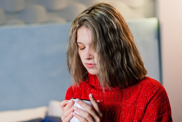 Getränke-, Weihnachts- und Hygge-Konzept - Nahaufnahme einer glücklichen Frau mit einer Tasse Kaffee im Bett zu Hause