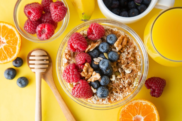 Getreide mit Früchten, Beeren zum Frühstück. Gesundes Frühstück, gelber Hintergrund.