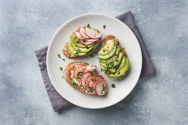 Getreidebrot-Sandwiches mit Hüttenkäse, frischer Avocado und Rettich.