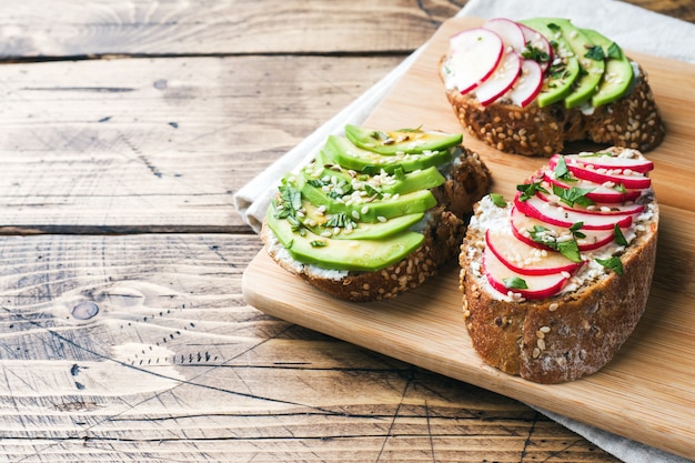 Getreidebrot-Sandwiches mit Hüttenkäse, frischer Avocado und Rettich.