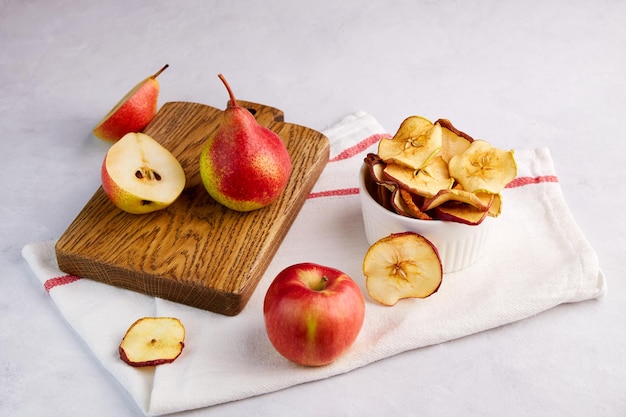 Getrocknete Apfel- und Birnenscheiben in einer Schüssel auf hellgrauem Hintergrund. Selbstgemachte Obstchips