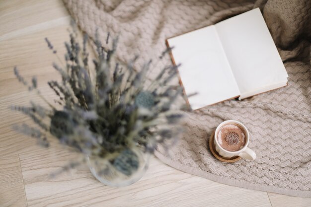 Getrocknete Blumen und eine Tasse Cappuccino mit Buch auf Draufsicht des hölzernen Hintergrundes