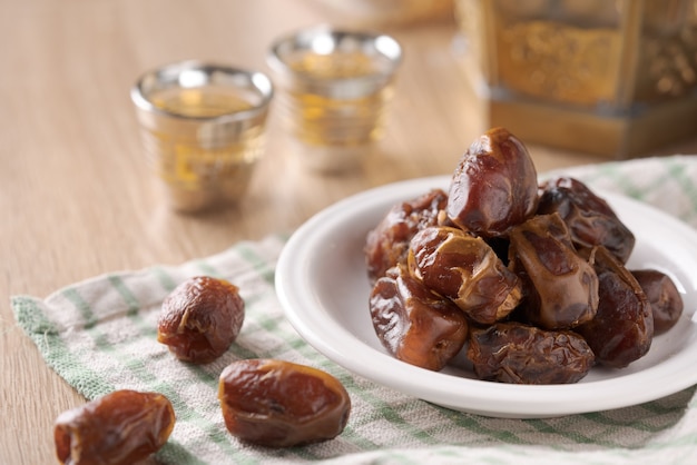 Getrocknete Datteln essen. Tasse Tee auf Holztisch. Traditionelles arabisches Essen für Iftar