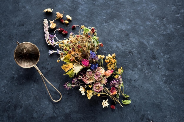 Getrocknete medizinische Kräuter und Blumen für Kräutertee auf einer Draufsicht des schwarzen konkreten Hintergrundes