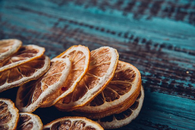 Getrocknete Orangenscheiben auf einem Holztisch, selektiver Fokus und getöntes Bild. Rustikaler blauer Holzhintergrund