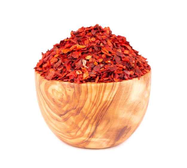 Getrocknete rote Chiliflocken in Olivenschale, isoliert auf weißem Hintergrund. Gehackte Chili-Cayenne-Pfeffer. Gewürze und Kräuter.