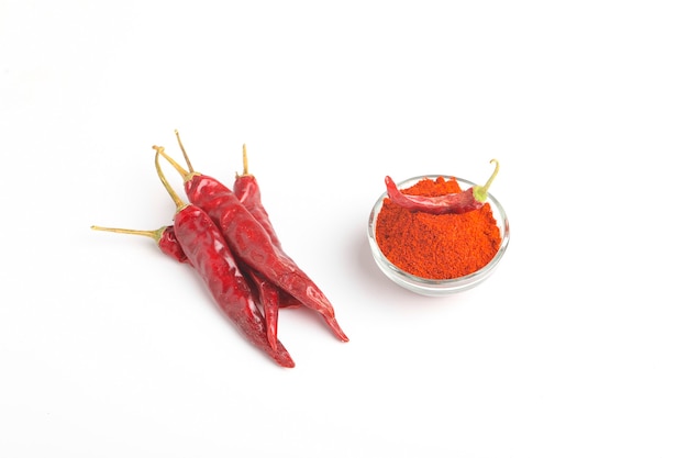 Getrocknete rote Chilis und Pulver in Glasschüssel auf weißer Oberfläche