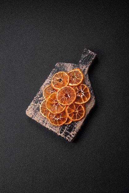 Getrocknete runde Mandarinen-Orangen- oder Zitronenscheiben auf dunklem Betongrund, Zutat für die Herstellung von Süßigkeiten