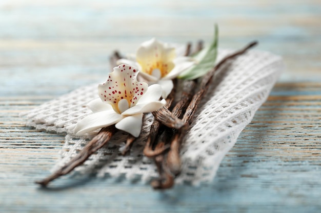 Foto getrocknete vanilleschoten und blumen auf holzhintergrund