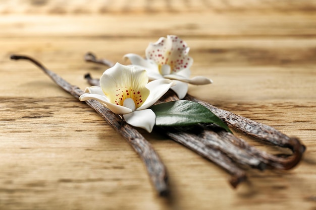 Getrocknete Vanilleschoten und Blumen auf Holzhintergrund