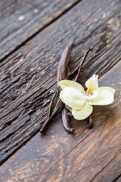 Getrocknete Vanillesticks und Vanilleorchidee auf Holztisch. Nahansicht.