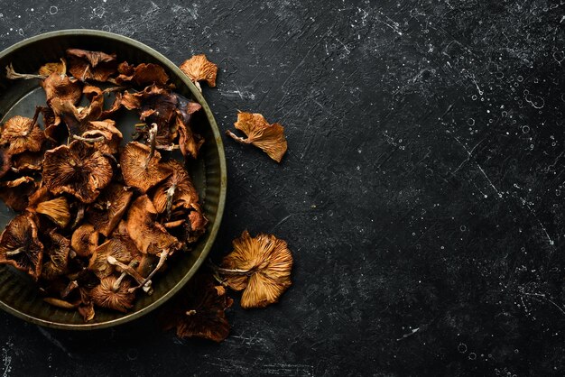 Getrocknete wilde Pilze auf schwarzem Steinhintergrund Herbstessen Draufsicht Freier Platz für Text