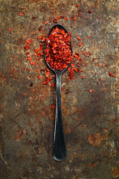 Foto getrockneter roter heißer paprika in einem metalllöffel gewürze und gewürze top-view auf einem rostigen hintergrund