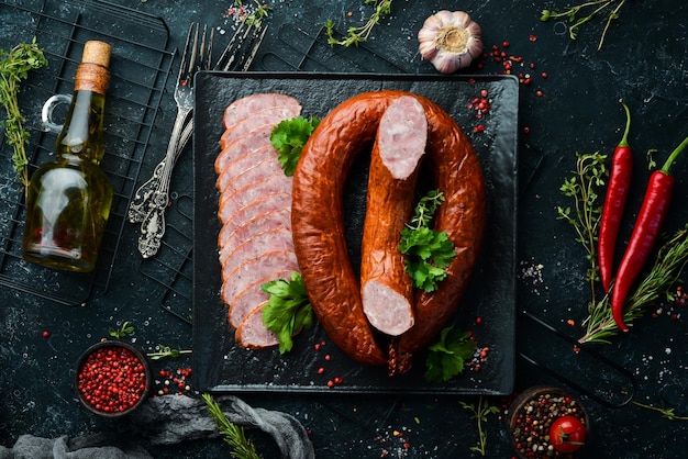 Getrockneter Salamiwurstring aus Schweinefleisch auf schwarzem Steinhintergrund Draufsicht Freier Platz für Text